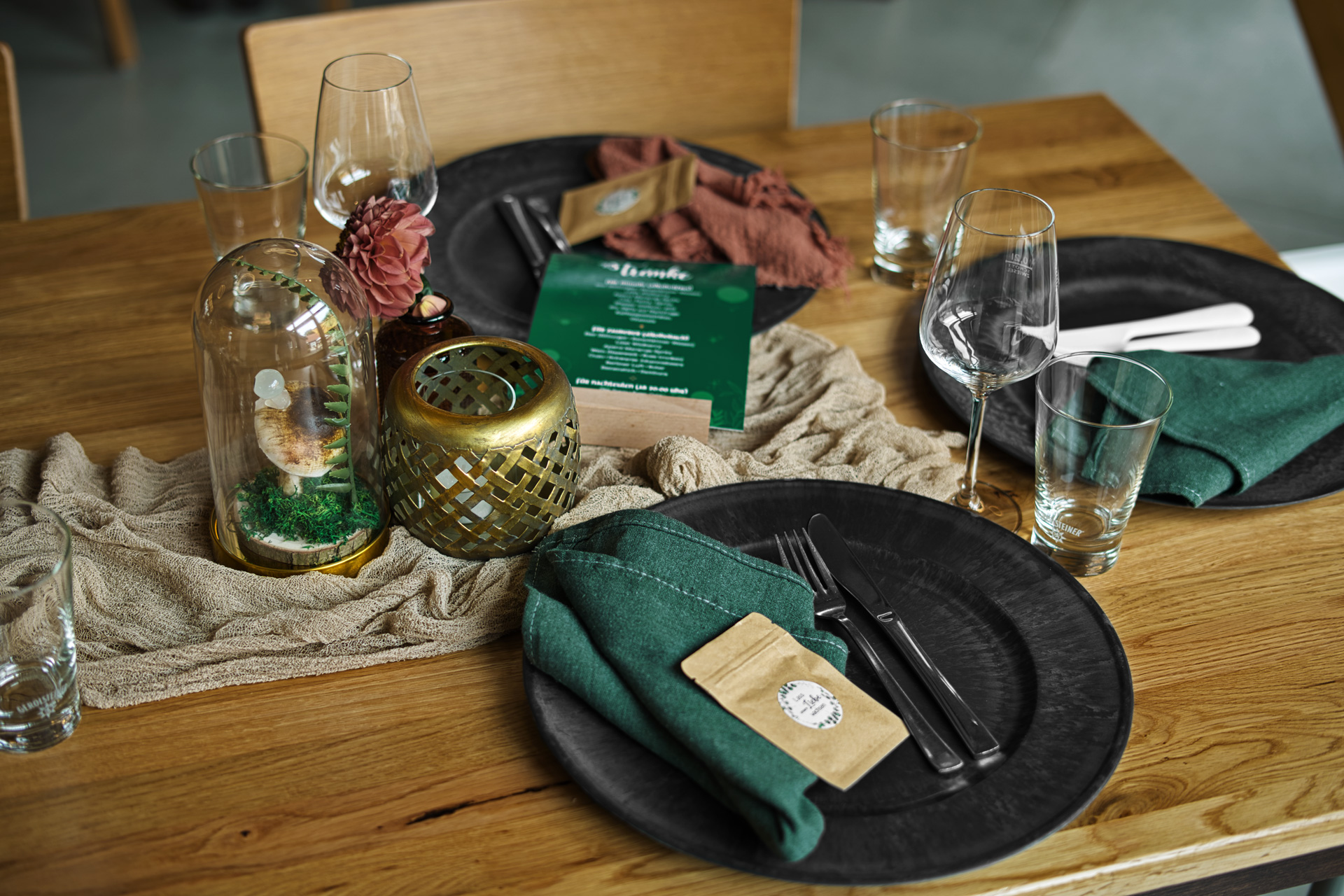 wedding set table with dark plates and a green menu for beverages