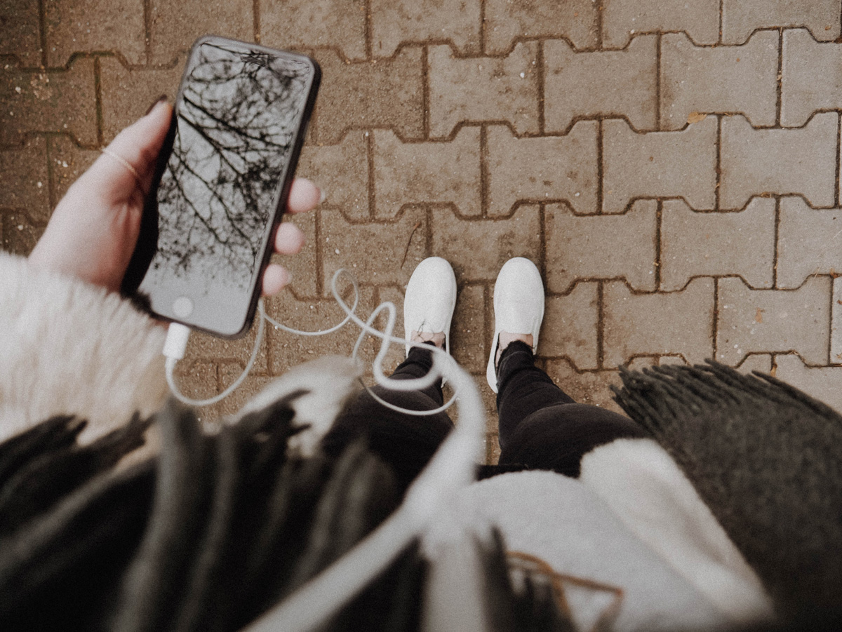 Woman looking down on her shoes an iPhone in her hand